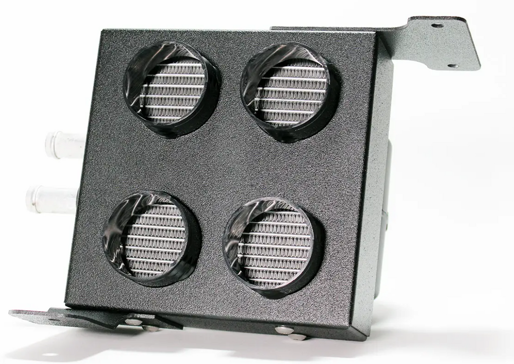 The Inferno Cab Heater Kit With Defrost for 2015-Current Kawasaki Mule Pro FX/FXT/FXR is a rectangular black metal box with four circular vent grilles, two short hose connectors on the left, and mounting brackets on top right and bottom left.