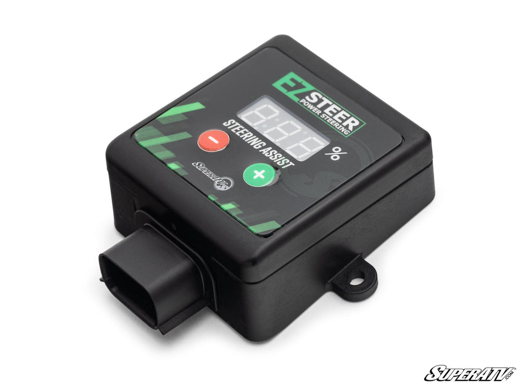 A black Sprint Car Adjustable Power Steering Assist Controller features a digital display, green plus and red minus buttons, a connection port, and the SuperATV logo in the corner. The device is shown on a white background.