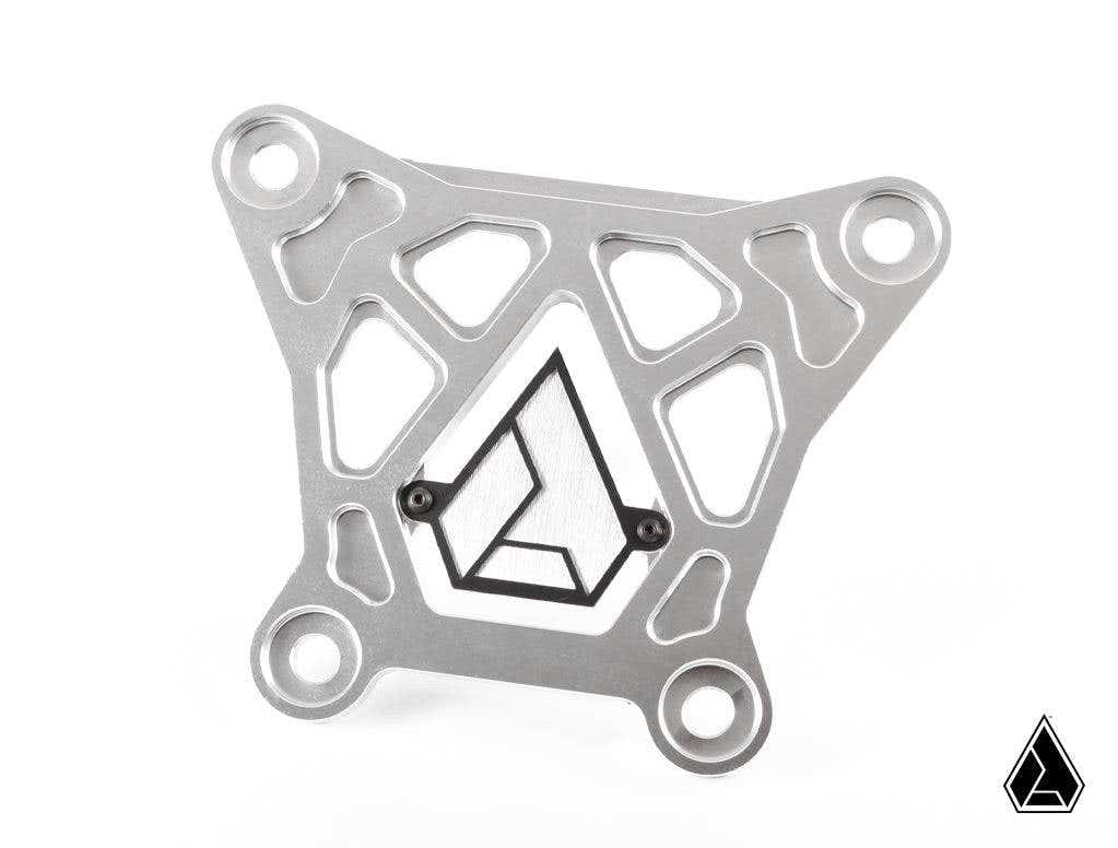 The Assault Industries Billet Radius Rod Reinforcement Plate (Fits: Turbo S) is a silver, geometric metal bracket with four rounded mounting holes, detailed cutouts, and a black and silver angular logo centered on a clean white background. The logo repeat