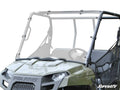 A close-up of a Polaris Ranger 500 Midsize (2010-2013) off-road utility vehicle features a clear, slightly angled windshield covering the front and top, black metal frame, and visible Polaris logo on the hood against a plain white background.