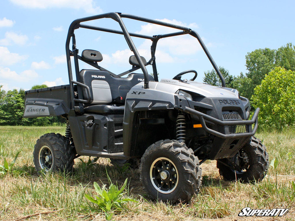 A Polaris Ranger XP equipped with a Polaris Ranger 2 Lift Kit is parked on grass. It’s gray, has two seats, a roll cage, rugged tires, and a rear cargo bed. The SuperATV logo is visible; trees and blue sky are in the background.