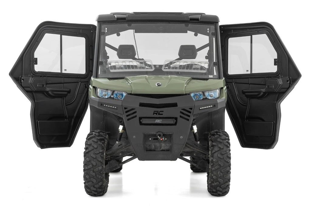 A green 2 Seater Can-Am Defender HD 5/HD 7/HD 8/HD 9/HD 10 is shown from the front with both doors open, featuring rugged tires, two visible front seats through the windshield, and an angular design with blue headlights.