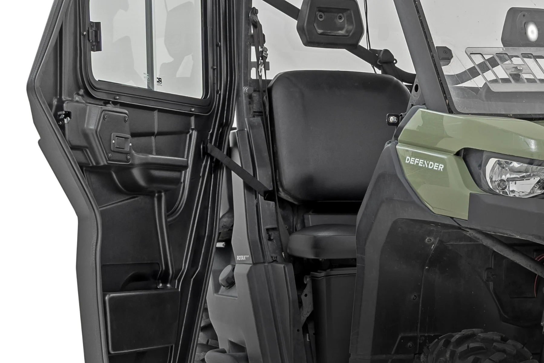 A close-up shows the open door of a 2 Seater Can-Am Defender HD 5/HD 7/HD 8/HD 9/HD 10, revealing the black interior with a plain seat, seatbelt, and dashboard. “DEFENDER” is printed on the vehicle’s side.