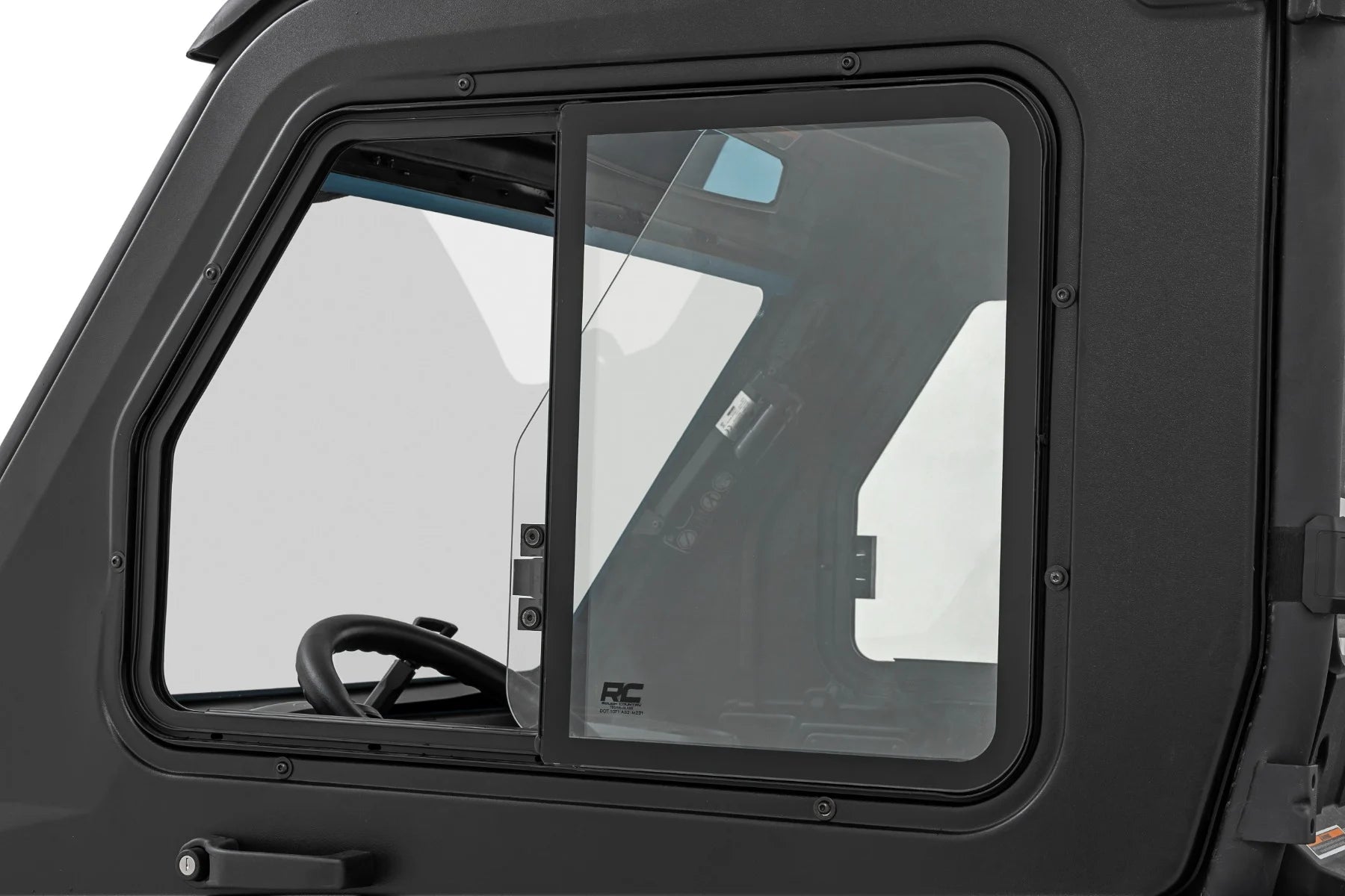 Close-up of a 2 Seater Can-Am Defender’s side window, partially open, featuring a sliding glass panel and black metal frame. The steering wheel and dashboard are visible inside; the matte black exterior is also shown. For HD 5/7/8/9/10 models.