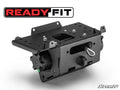 A black, heavy-duty mounting bracket for the Can-Am Maverick R Ready-Fit Winch features multiple holes, a locking pin, and adjustment knobs. It sits below a bold READY FIT logo; SuperATV branding is at the bottom right on a white background.