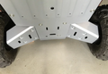 Close-up of Honda Pioneer 1000 Alloy Rear A Arm Guards (2022+) installed beneath the vehicle, showing clean, silver metal guards securely bolted to the frame between large tires, with protective angles and cutouts for ventilation or mounting.