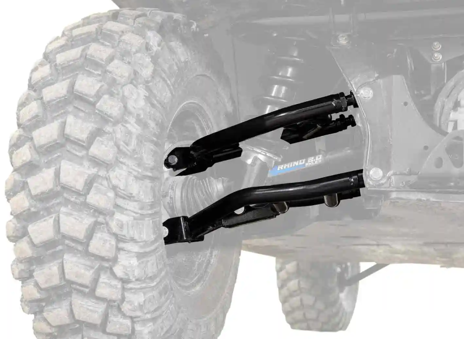 Close-up of Defender HD10 1.5 Rear Offset A-Arms and coil springs on an off-road vehicle, attached to a large, knobby tire. The background and tire are faded to emphasize the upgraded suspension components.
