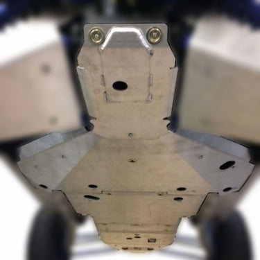 Close-up of a Ricochet Off-Road Full Frame Aluminum Skid Plate Set installed on a 2018-19 Polaris Rzr Xp Turbo S, showcasing bolted metallic panels with circular cutouts that protect the undercarriage. Wheels are partially visible at the edges.