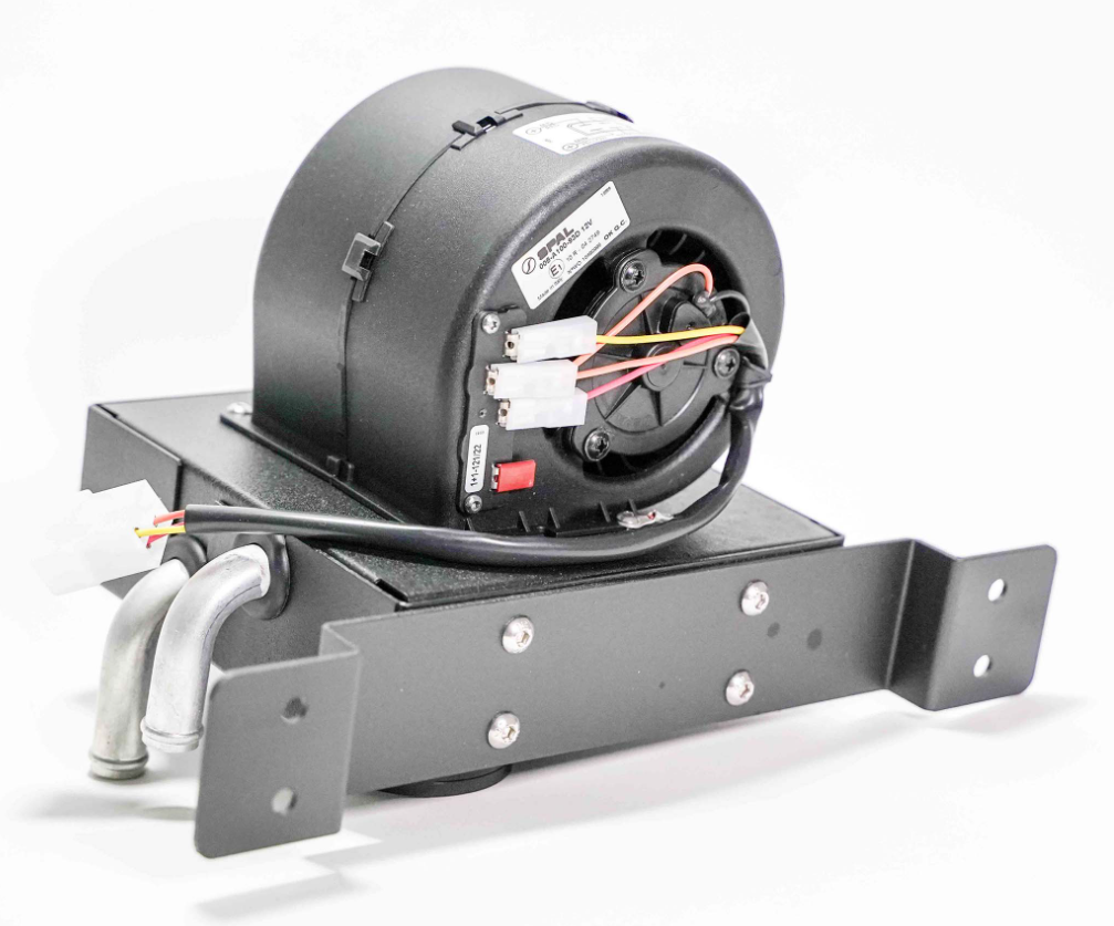 The Yamaha Wolverine RMAX Cab Heater with Defrost (2020-Current) features a black, cylindrical blower motor mounted on a metal bracket with two curved pipes, multiple screws, and colored wires connecting to white plastic connectors against a plain white b