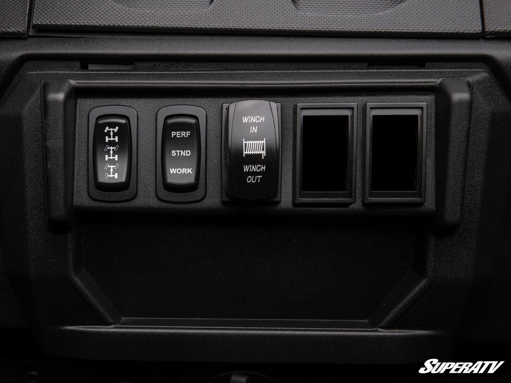Close-up of a rugged dashboard panel with four black switches—differential lock, mode selector, winch control, and two blanks—featuring Polaris Ranger 1000 Rocker Switch Adapters. The SuperATV logo appears in the lower right corner.