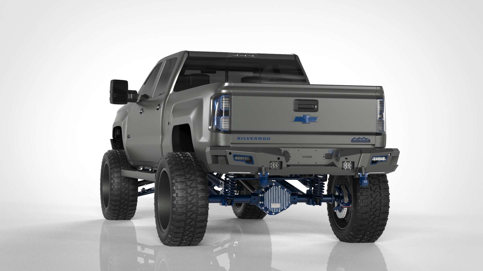 A lifted gray Silverado is shown in a studio with oversized off-road tires, blue accents, and a 2015-2019 Chevy/GMC 2500 Identity Rear Bumper Full Kit featuring shackle end pods, rings, and black accent lights.