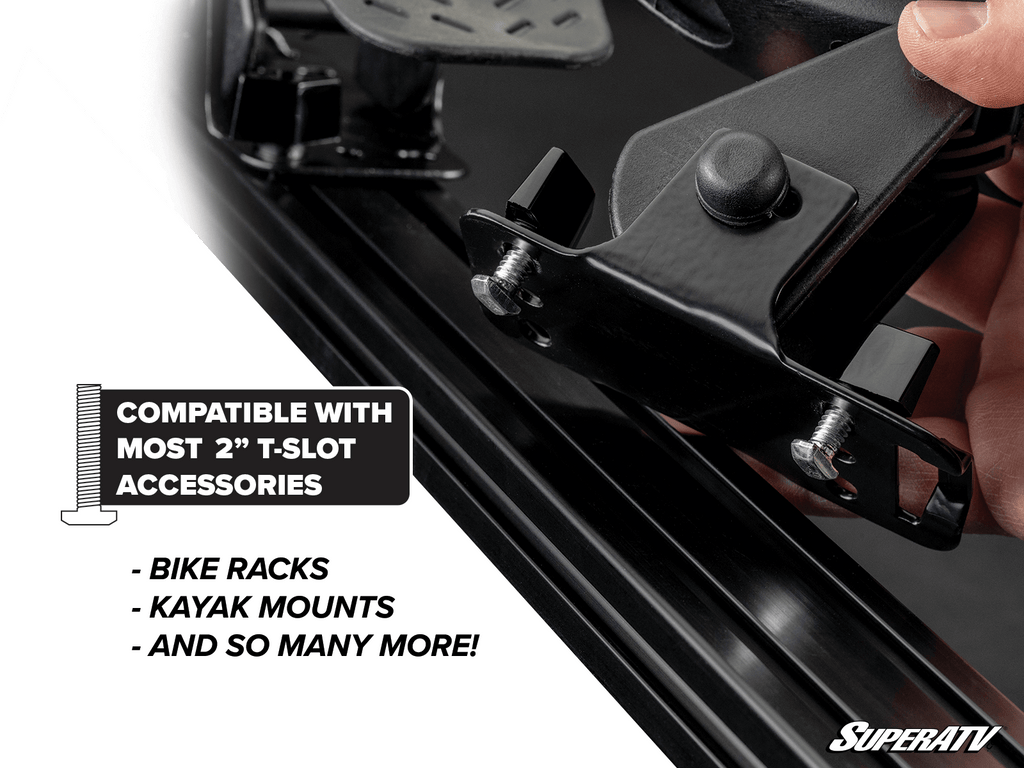 A hand attaches a black metal bracket to a T-slot track on the Can-Am Maverick X3 MAX Outfitter Sport Roof Rack. Text: Compatible with most 2” T-slot accessories—bike racks, kayak mounts, and more! SuperATV logo at bottom right.