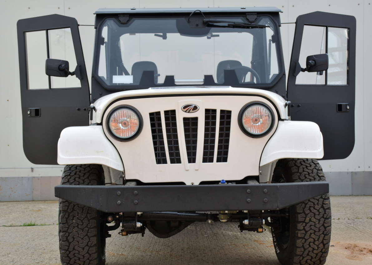The ROXOR2 Full Hard Enclosure Cab Kit by Hardcabs is shown on a white off-road vehicle, front view, with both doors open. Features include round headlights, black grille, rugged tires, and Mahindra logo; background is plain with concrete ground.