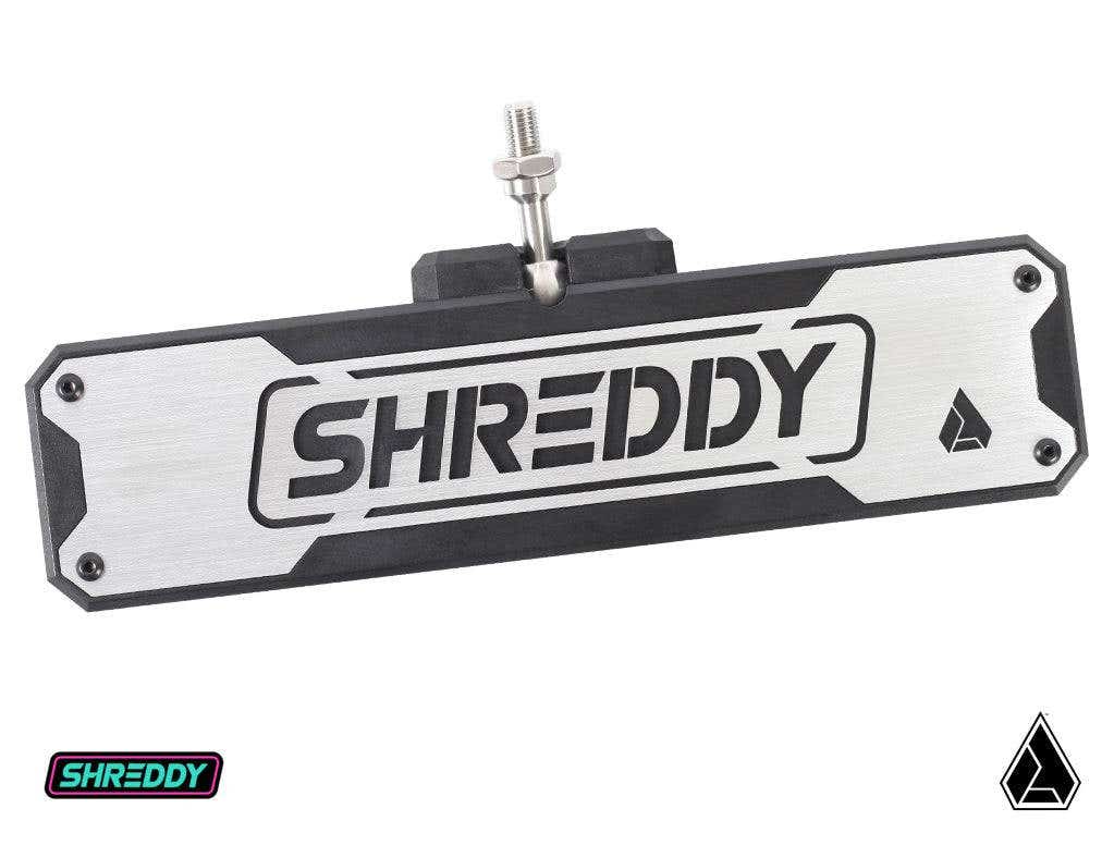 The Assault Industries SHREDDY Bomber Convex Center Mirror features “SHREDDY” cut out in bold letters, beveled corners, a black border, and a triangle logo on the right. The mirror mounts with a central bolt; two logos appear in the image corners.