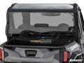 A Polaris General 1000 with a black exterior features a transparent rear vented windshield, rear cargo bed, and a visible SuperATV logo on the bottom right. The word “GENERAL” is partially seen on the vehicle’s upper rear side.