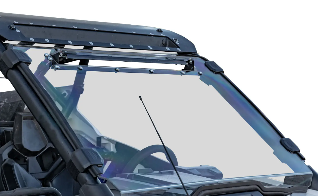 Close-up of a Polaris RZR Pro XP Scratch Resistant Vented Full Windshield with clear glass, visible bolts, and wipers on a utility vehicle’s metal roof and frame; the steering wheel and dashboard are visible through the windshield. Background is plain whi