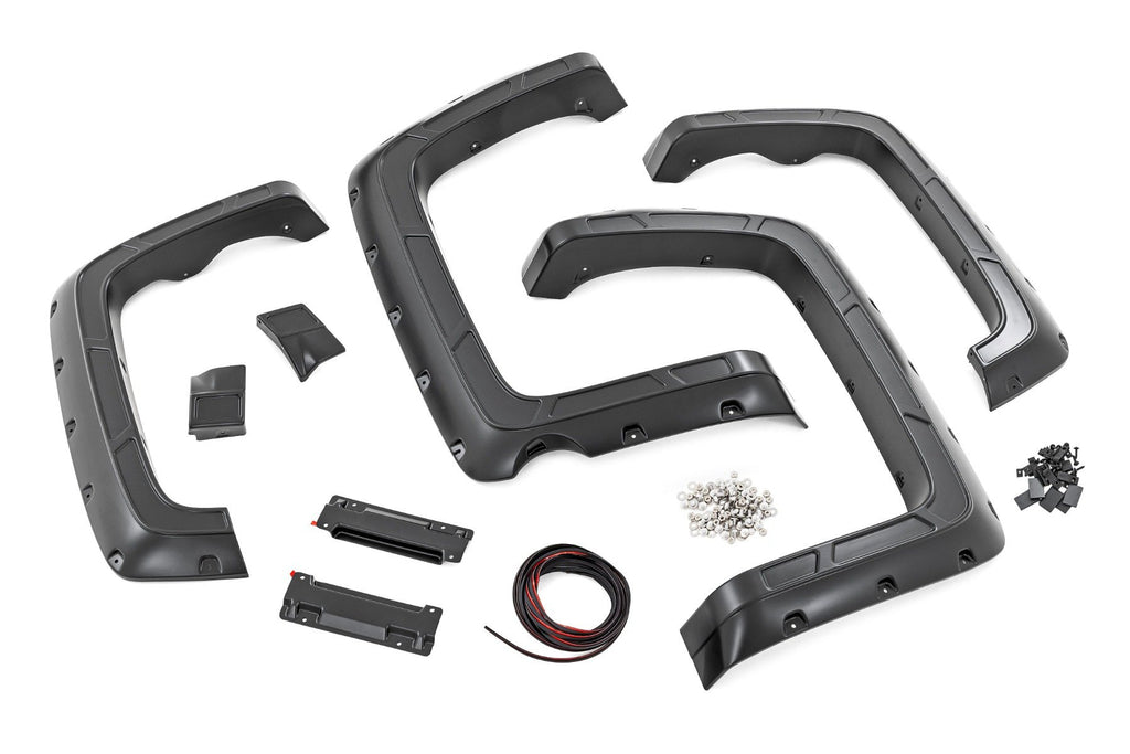 Displayed on a white background are four black plastic fender flares, mounting brackets, screws, wiring, and clips—components from the Fender Flares | Defender 59 Bed kit for Chevy Silverado 1500 2WD/4WD (2014-18 & Classic).
