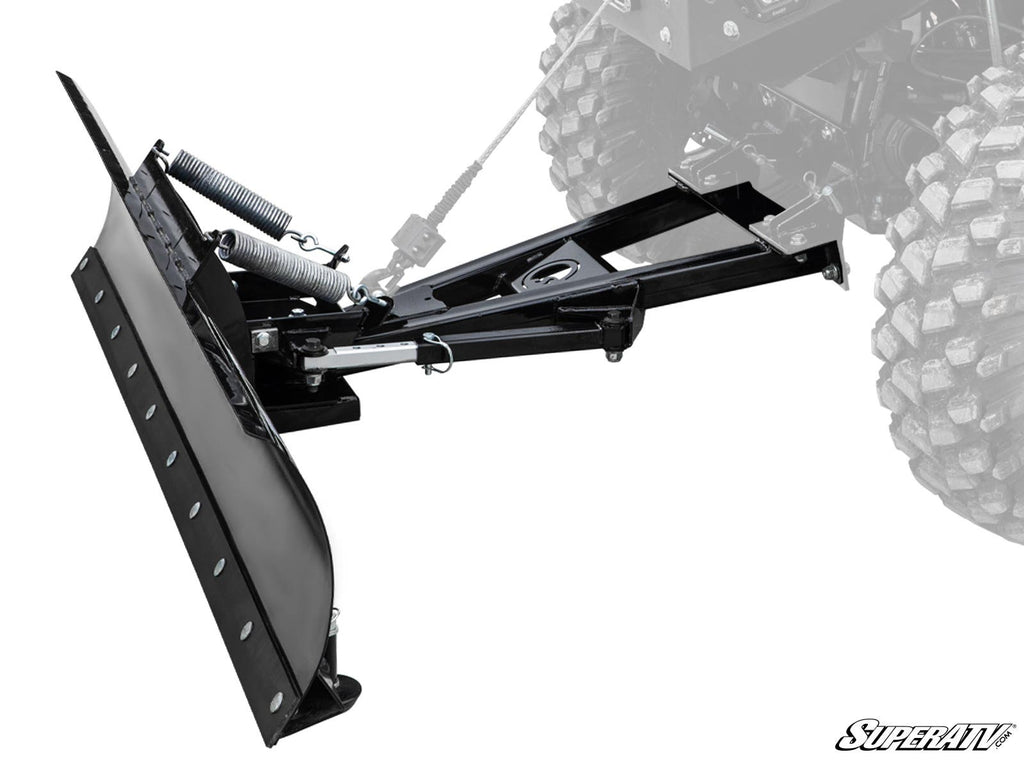 A close-up of the Plow Pro Snow Plow Blade and Frame Kit in black metal, attached to an off-road vehicle with rugged tires. The blade features tension springs, a mounting frame, and displays the SuperATV logo at the bottom right. Vehicle is partially visi