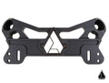 The Assault Industries F-22 Heavy Duty Shock Tower Brace Kit for Can-Am Maverick X3 is a black CNC-machined metal part with angular cutouts, a central geometric triangle logo, multiple mounting holes, and smooth edges on a white background.