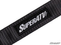 A close-up of a SuperATV Limit Strap shows a black woven strap with a rectangular black patch displaying “SUPERATV.COM” in white. The patch is sewn onto the strap, and a small SuperATV logo appears in the bottom right corner.