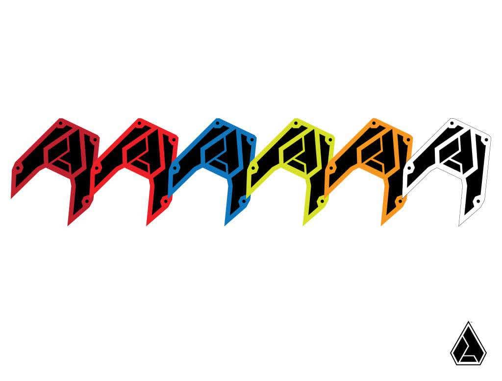Six geometric, angular shapes styled like the Assault Industries B2 Bomber Bezel Set appear in red, pink, blue, green, yellow, and white with black accents. A smaller version is shown in the lower right on a white background.