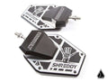 Two Assault Industries SHREDDY B2C Convex Side Mirrors with black angular mounts, silver bases featuring a white skeleton hand graphic, geometric cutouts, and mounting bolts. A small black triangle logo appears in the bottom right corner.
