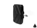 The Assault Industries Explorer Series UTV Side Mirrors feature a black, rectangular design with angled grooves, mounted on a metal bracket with bolt and knob. Set against a plain white background, a small black triangular logo appears in the lower right 