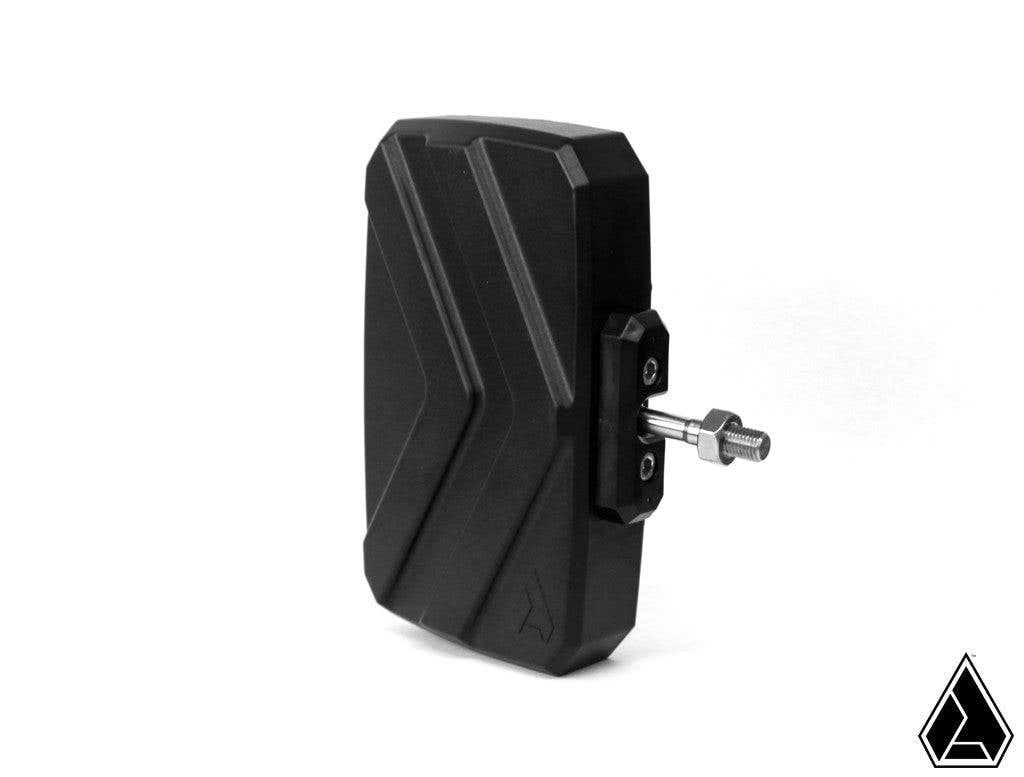 The Assault Industries Explorer Series UTV Side Mirrors feature a black, rectangular design with angled grooves, mounted on a metal bracket with bolt and knob. Set against a plain white background, a small black triangular logo appears in the lower right 