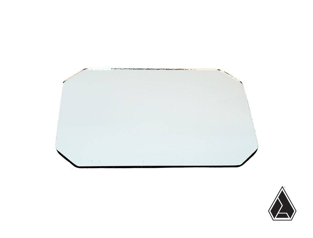 A rectangular Assault Industries Explorer Series Mirror Glass Replacement with beveled corners lies flat on a white background. In the bottom right corner, theres a black outlined prism-shaped logo.