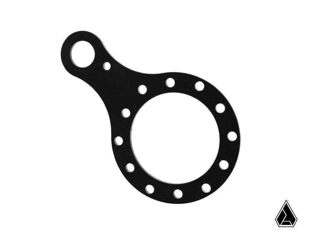 The Assault Industries Push-To-Talk Communications Plate (PTT Plate // Black) is a flat, black circular metal plate with an off-center tab featuring a small hole and evenly spaced holes around the rings edge. A black triangular logo appears at the bottom 