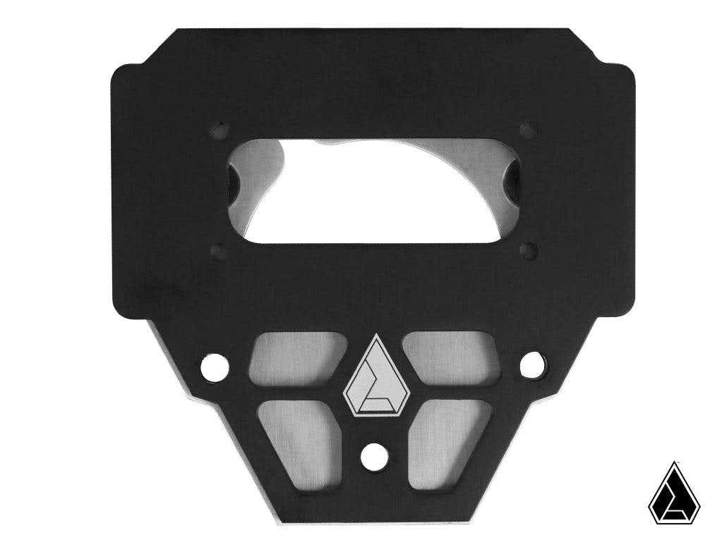 The Assault Industries Switch Pro Steering Wheel Mount is a black metal plate with geometric cutouts, several circular holes, and a large top rectangular opening. The Assault Industries emblem appears twice on the lower right against a white background.