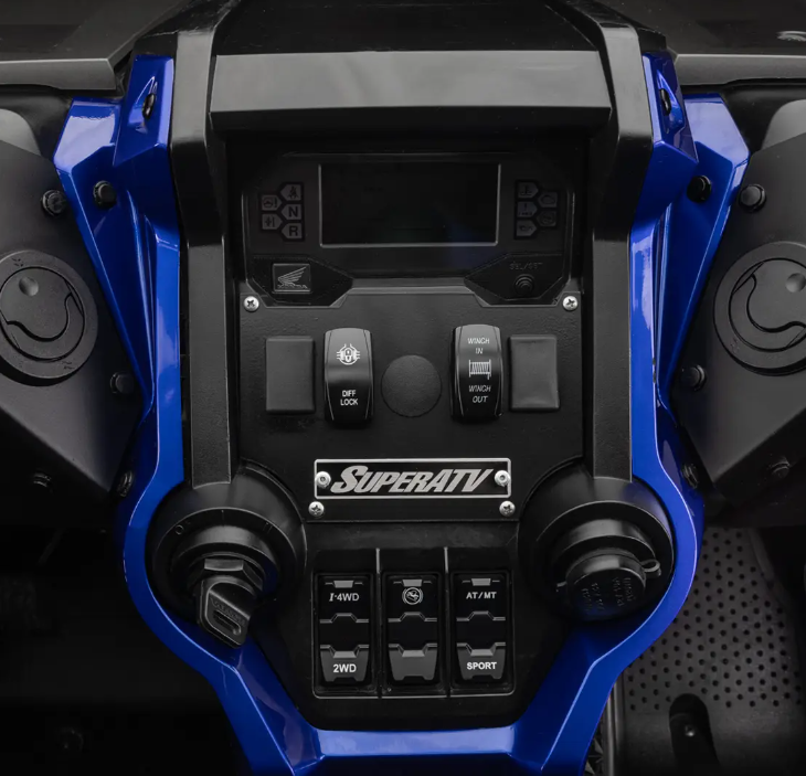 Close-up of a blue Honda Talon 1000 dashboard with the In-Dash Heater installed, showing multiple switches, buttons, a digital display, 2WD/4WD/Sport mode controls, auxiliary ports, and a SuperATV logo near the bottom center.