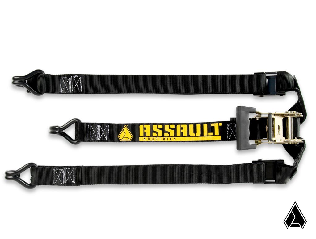 A black Assault Industries Rugged Y Strap (Fits: Adventure Rack; OG Spare Tire Rack) features heavy-duty construction, metal hooks on both ends, reinforced stitching, a metal ratcheting mechanism, and a yellow logo in the center.