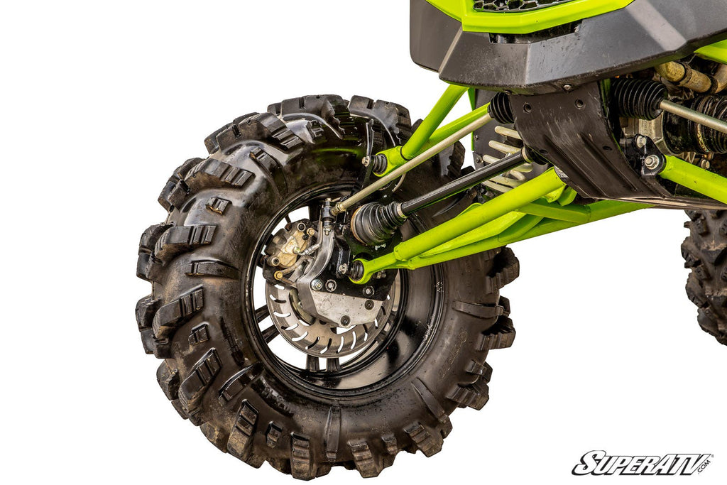 Close-up of a Textron Wildcat XX 6 Portal Gear Lift’s front left wheel with deep tread tires, visible suspension, disc brake, axle, and green chassis parts. Image has a white background with the “SuperATV” logo in the corner.