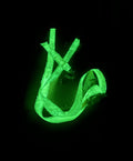 The GLOSTRAP, the world’s first glow-in-the-dark ratchet strap, glows bright green against a black background, partially coiled so its luminescent material is clearly visible.