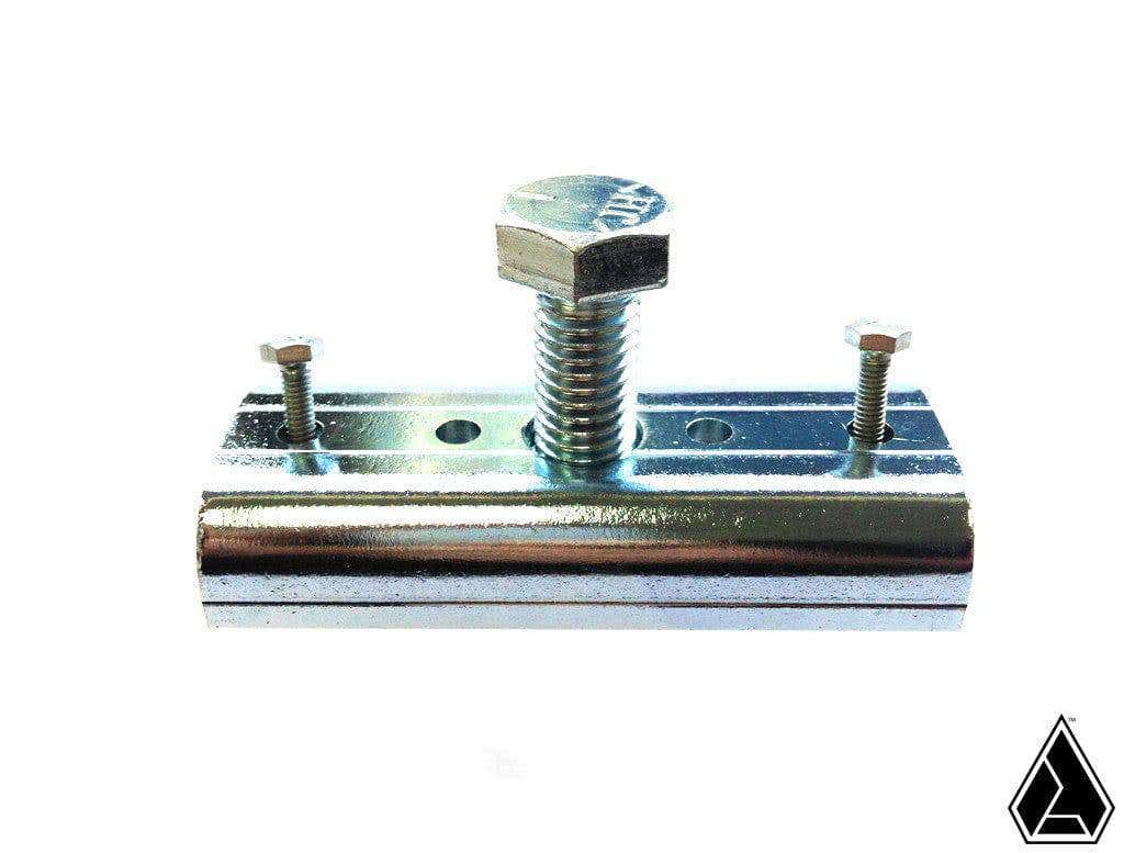 The Assault Industries Steering Wheel Removal Tool is a shiny, reflective, cylindrical metal clamp with two small screws on each end and a large hex bolt in the center, shown on a white background with a black geometric logo in the lower right.
