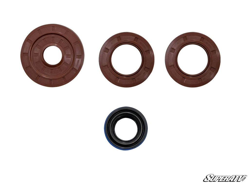 Four circular seals for the Polaris RZR Transmission Seal Kit are displayed on a white background: three brown seals of different sizes in the top row and one smaller black and blue seal in the bottom row. The SuperATV logo appears at the lower right.