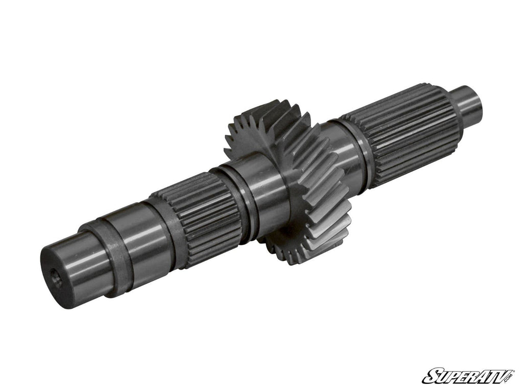 A Polaris Transmission Gear Reduction Kit shaft with cut gears and splined sections, two large helical gears near the center, and precision-machined surfaces. White background with the SuperATV logo in the bottom right corner.
