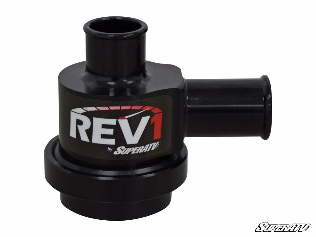 The SuperATV Turbo Charged Blow Off Valve is a black, cylindrical part with two short tube connections and features REV1 by SuperATV in bold white and red lettering on the side. The SuperATV logo appears in the image’s bottom right corner.