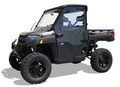 The Polaris Ranger Full Size (XP/Premium 1000) Framed Door Kit (2018+) is shown on a white background, featuring a black off-road vehicle with large rugged tires, reinforced windshield, canvas door cover, Ranger markings, and raised suspension.