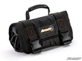 A black Pouch Roll-Up Tool Bag sits on a white background. It has orange stitching, a top carrying handle, two large black buckles, and a rectangular SuperATV logo patch on the front. The bag looks durable and neatly rolled up.