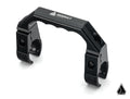 The Assault Industries UTV Grab Handle, made of black metal and contoured with ASSAULT branding, features dual clamp sections with screws. Its displayed on a white background with a geometric logo in the lower right corner.