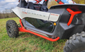 A close-up of Segway Villain with 1/4 polycarbonate lower doors, rugged tires, and red roll cage. The white and black body features bold SEGWAY decals, set on grass with trees in the background.