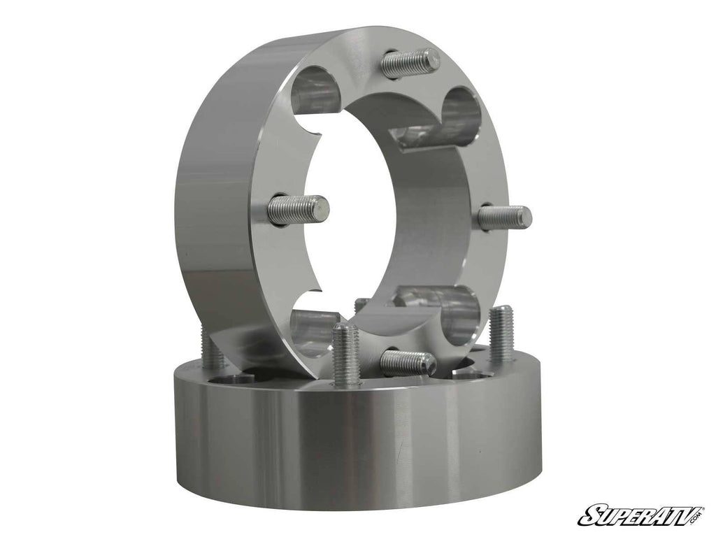 Two metallic, cylindrical Suzuki 2 Wheel Spacer - 4/110 units with threaded studs are stacked vertically on a plain white background. Their shiny machined surfaces reflect light. The SuperATV logo appears in the bottom right corner.