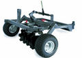 The ATV/UTV Disc Harrow 5 features a sturdy gray frame, large ridged tires, two angled rows of black notched discs for soil tilling, and a hydraulic cylinder for disc adjustment. The IDEAL brand name is visible on the side.