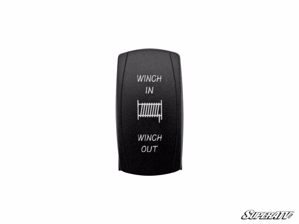 The Winch Rocker Switch Replacement is black with “WINCH IN” above and “WINCH OUT” below a white winch icon. The background is white, and a small “SuperATV” logo appears in the bottom right corner.