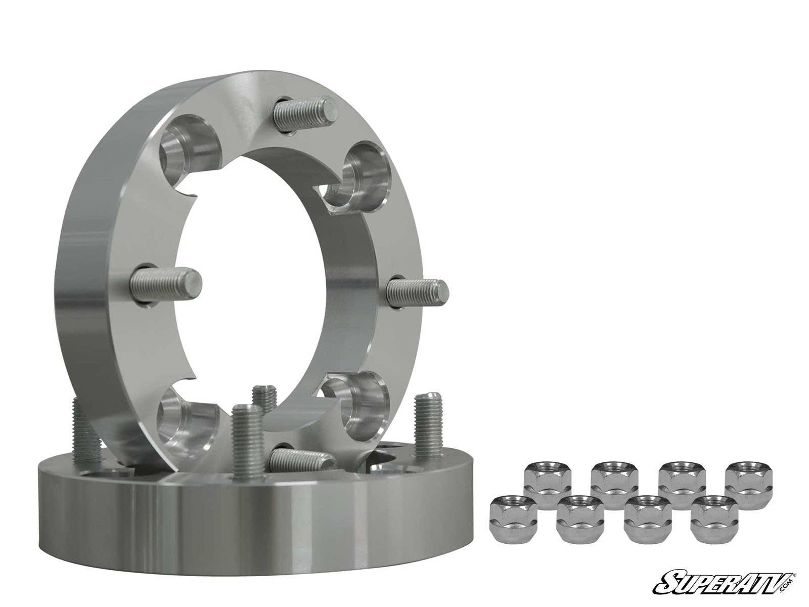 Two Kawasaki Wheel Spacer 4/156, 4/136, & 4/110 units with protruding studs are displayed in front. Eight chrome lug nuts are aligned to the right. The SuperATV logo appears at the bottom right on a white background.