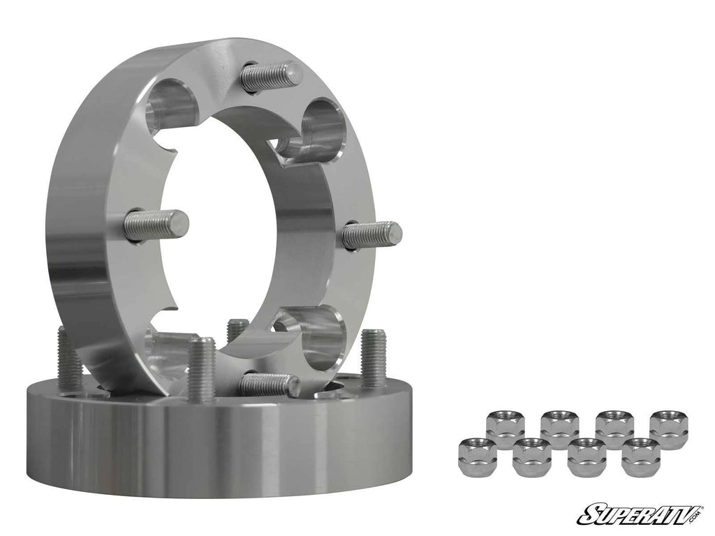 Two Honda Wheel Spacer 4/136 & 4/110 units with exposed wheel studs and a machined silver finish are stacked together, alongside eight matching lug nuts. The SuperATV logo is in the bottom right on a white background.