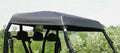A close-up of the Arctic Cat Prowler 700 - Soft Top shows its black fabric canopy secured with straps on the roof, as the off-road vehicle sits outdoors surrounded by green trees beneath a cloudy sky.
