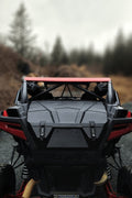 A JEMCO PXP Xtreme UTV Rear Cargo Box is installed on a Polaris RZR Pro XP, parked on gravel among blurred leafless trees and brown brush under an overcast sky. The image highlights the vehicles rugged rear design and suspension.